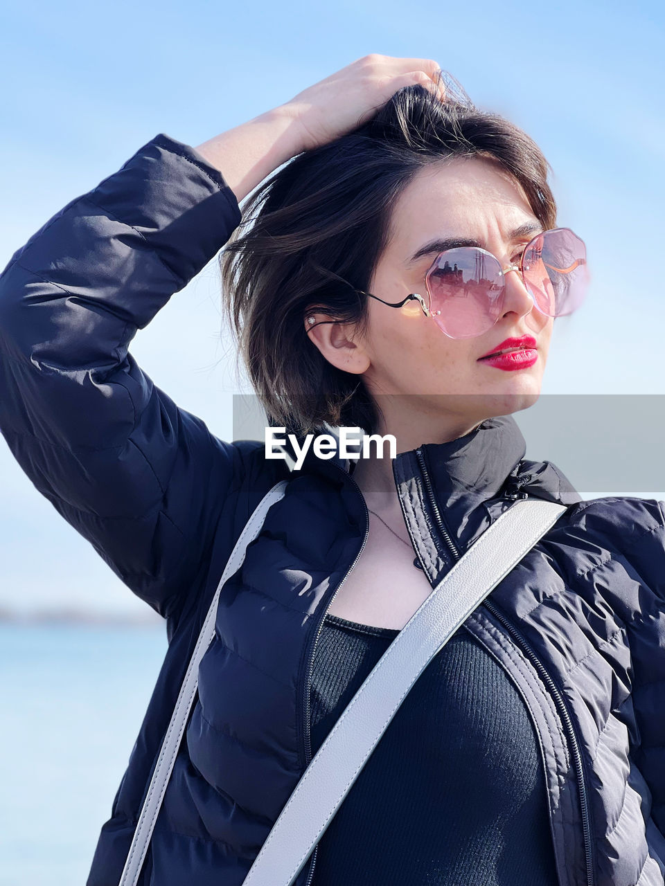 Portrait of young woman standing against sky