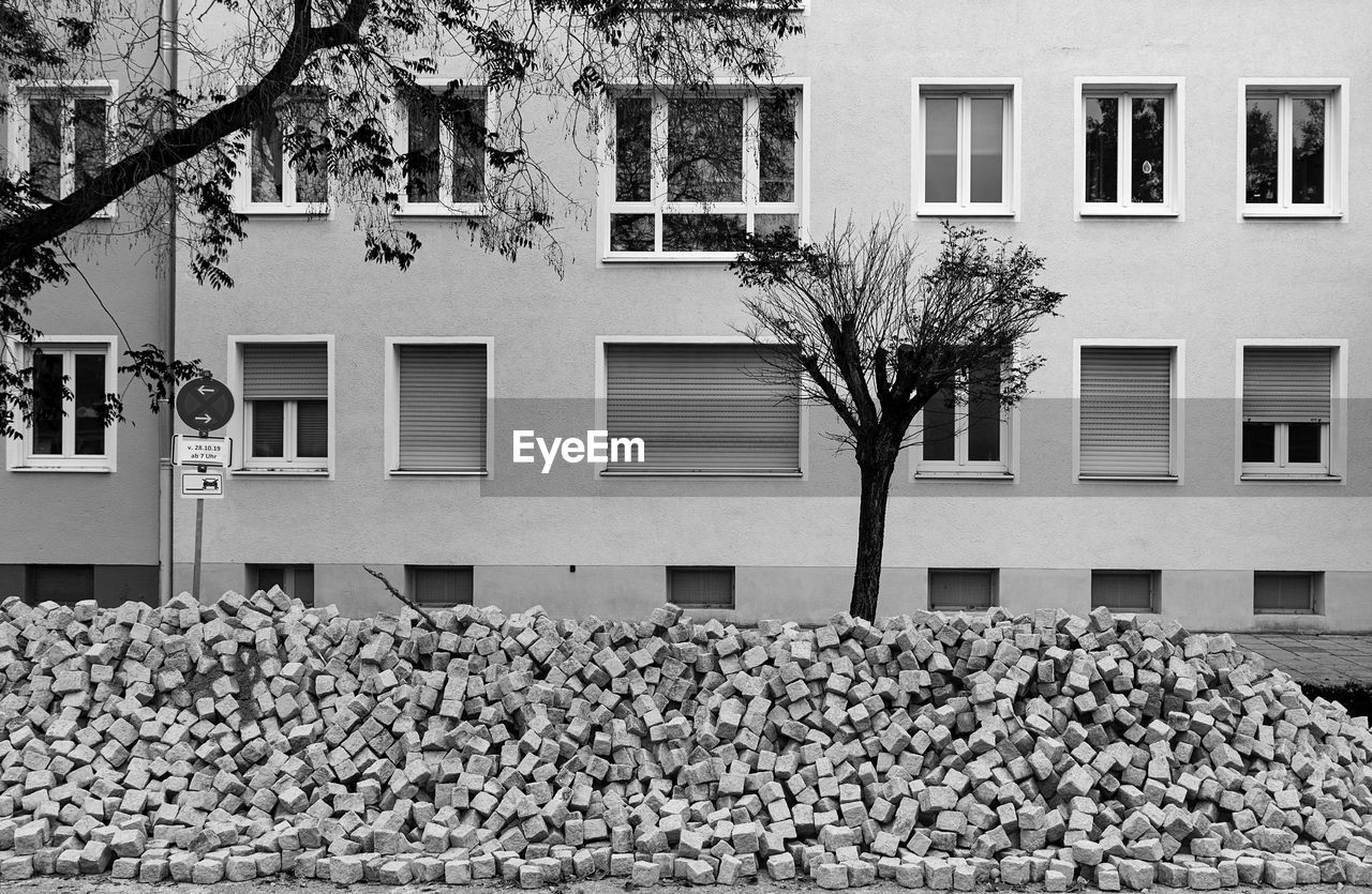 Tree in front of a house facade and a pile of bricks