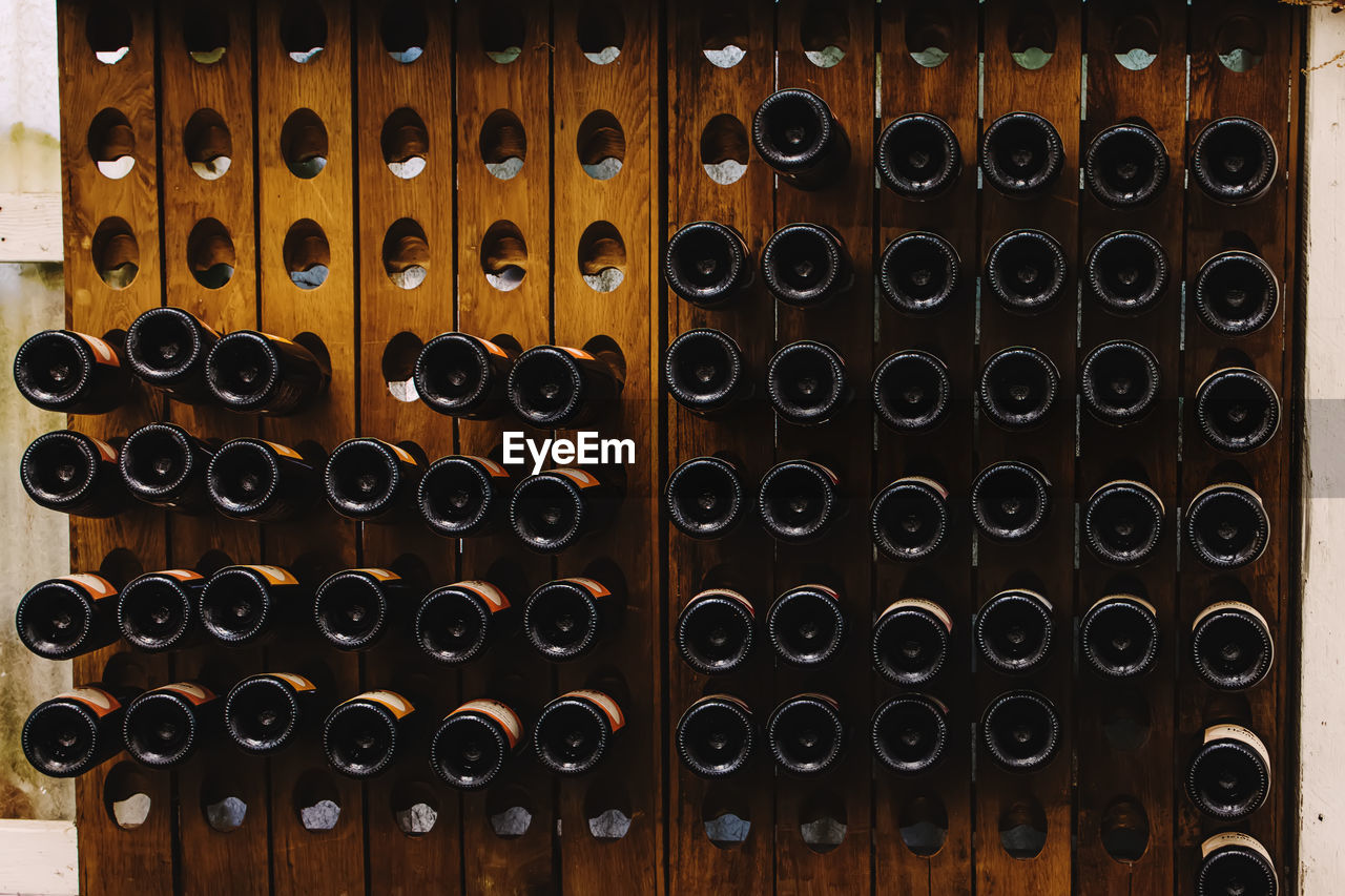 Bottoms of wine bottles in a wooden holder in a wine store