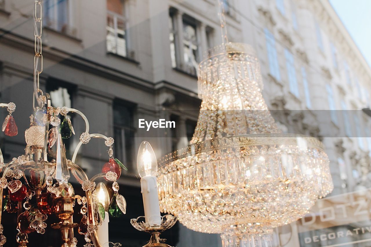 LOW ANGLE VIEW OF ILLUMINATED CHANDELIER HANGING FROM CEILING