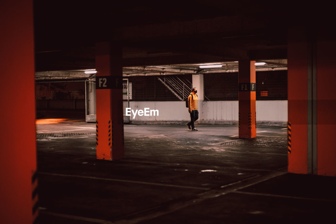 Rear view of man standing by building in garage