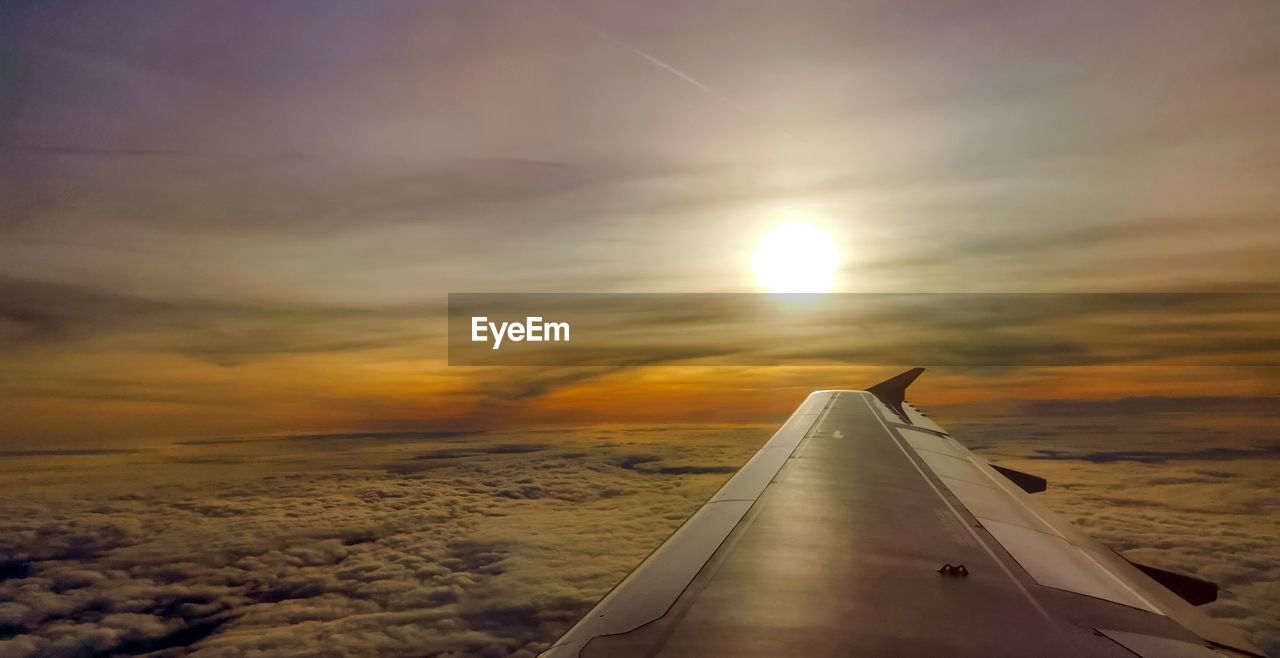 AIRPLANE FLYING OVER SEA DURING SUNSET