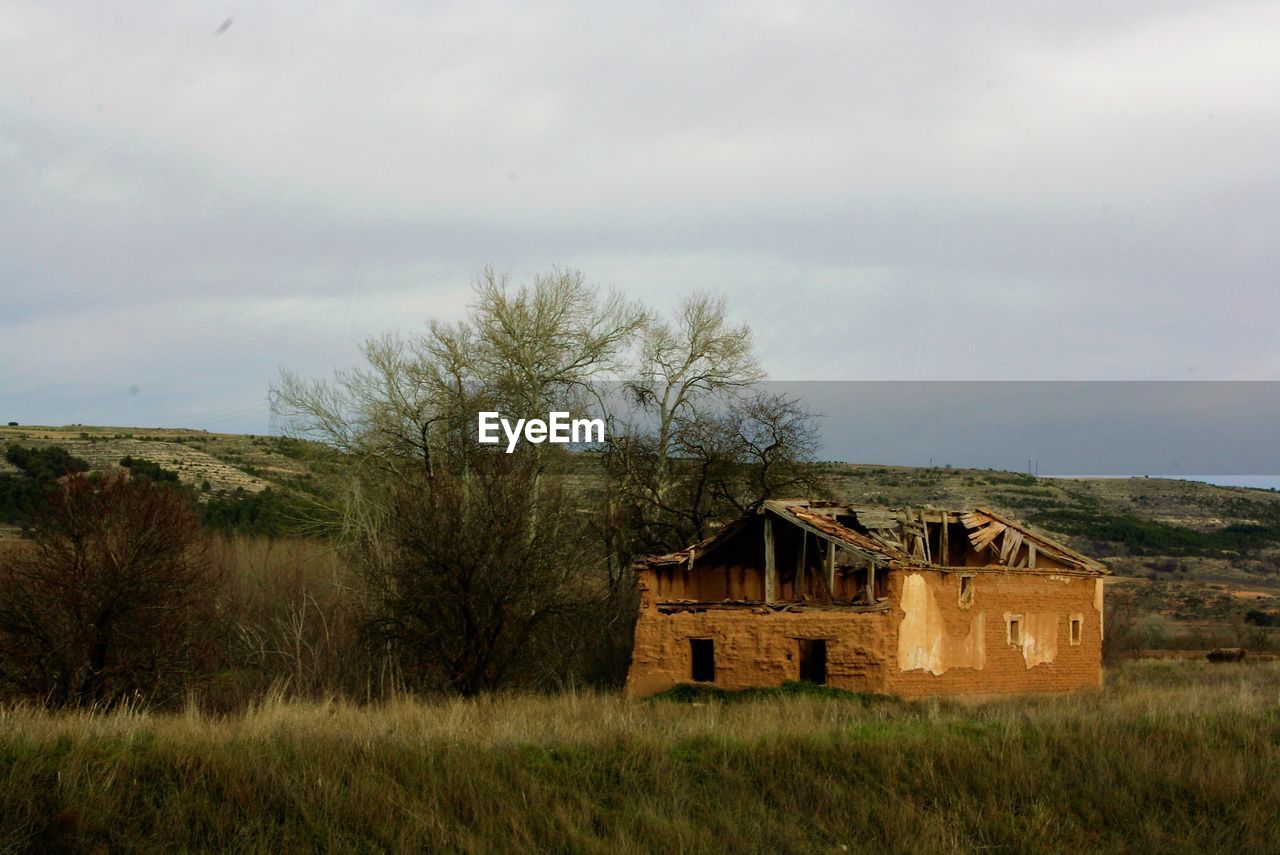 Abandoned house on field against sky