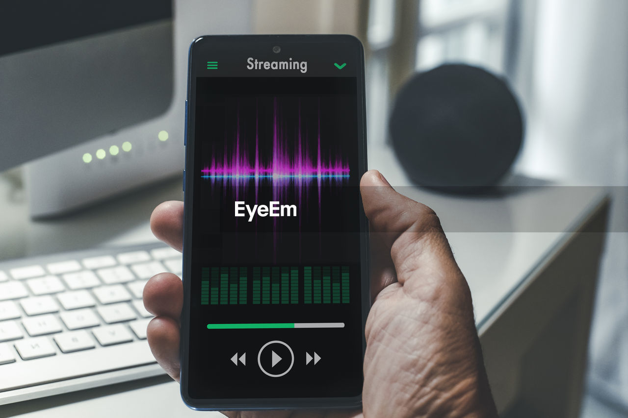 Smartphone in hand playing music. radio broadcast audio and sharing sound streaming concept.