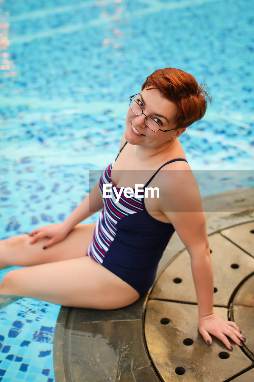 Portrait of smiling woman sitting at poolside