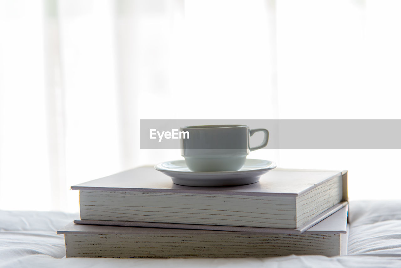 COFFEE CUP ON TABLE AGAINST WHITE BACKGROUND