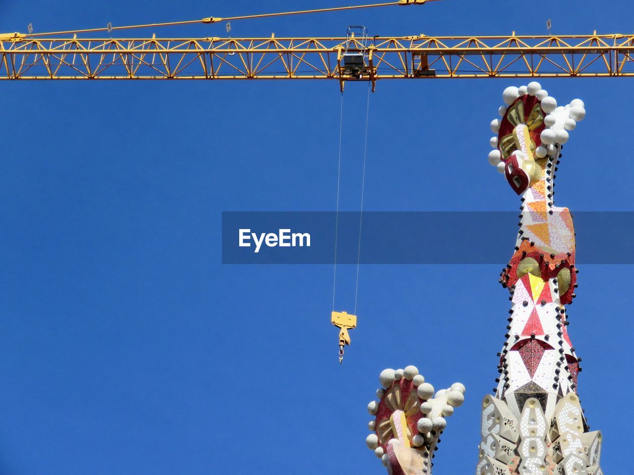 Low angle view of crane at sagrada familia during renovation against sky