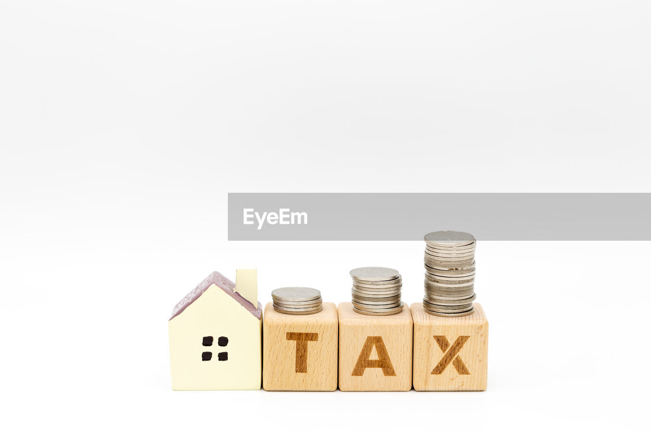 Close-up of toy blocks with coins and model home against white background