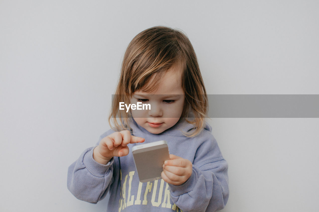 portrait of cute girl playing with toy against wall