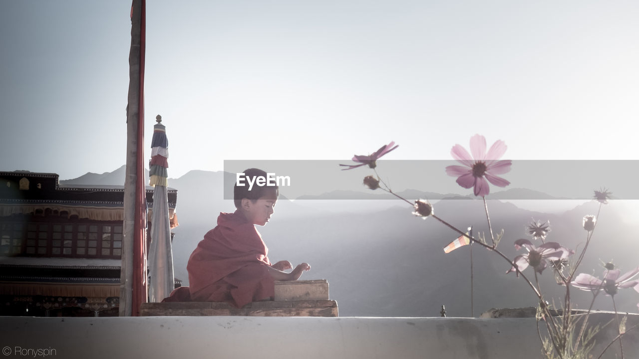 REAR VIEW OF GIRL WITH FLOWERS IN BACKGROUND