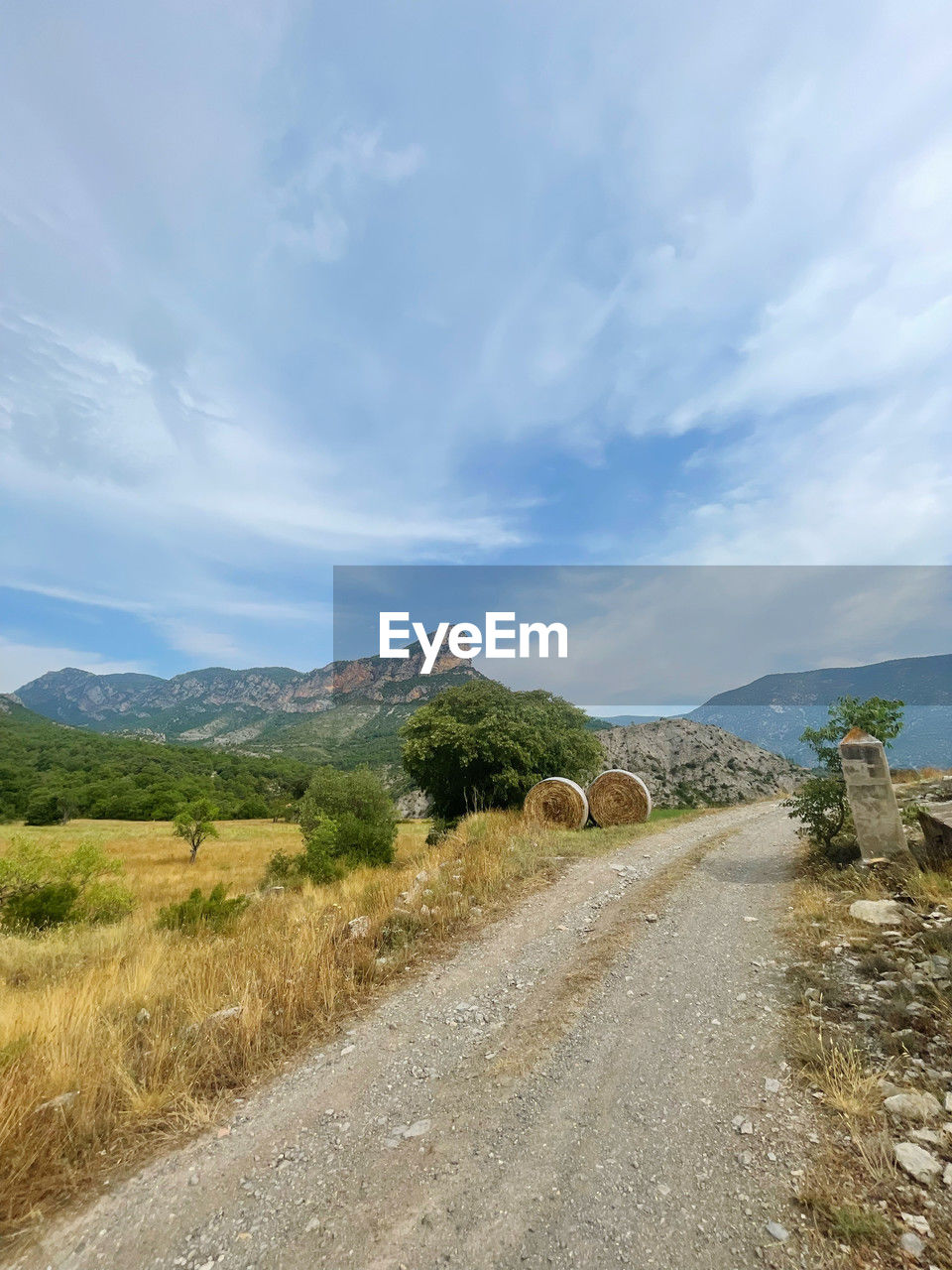 sky, cloud, landscape, environment, road, hill, scenics - nature, nature, transportation, beauty in nature, rural area, land, plant, the way forward, no people, non-urban scene, tranquility, tranquil scene, day, dirt road, travel, coast, sea, ridge, outdoors, horizon, travel destinations, grass, mountain range, plateau, remote, valley, footpath, tree