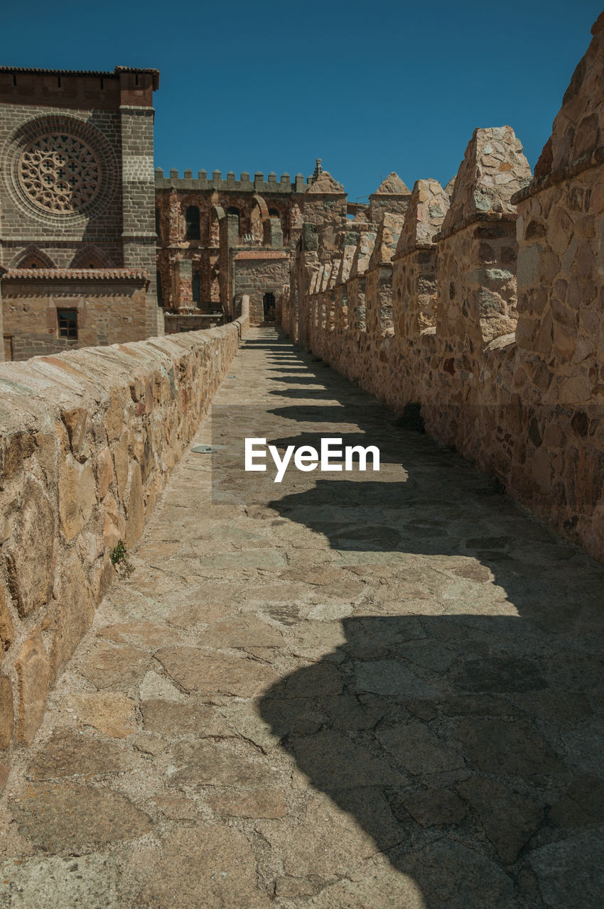 Pathway over stone wall with battlement around the town and side view of cathedral in avila, spain.