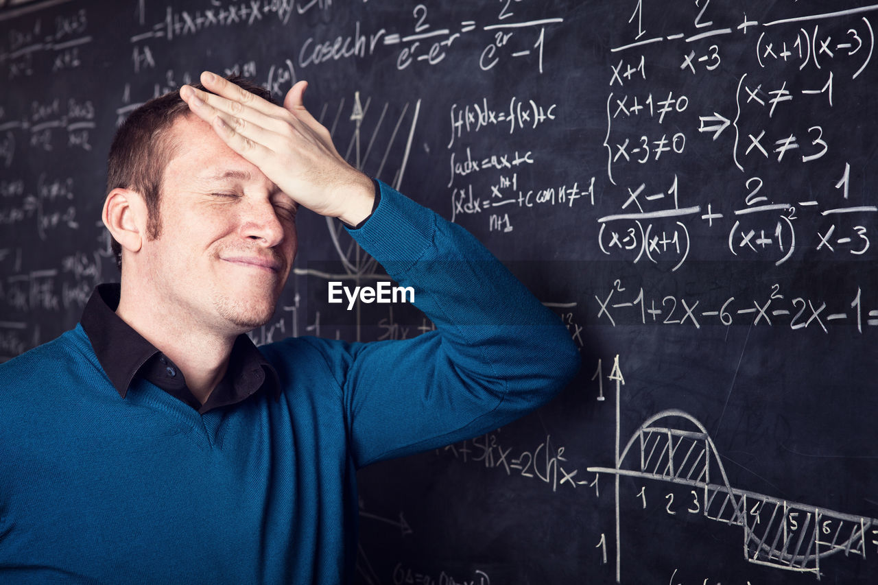 Professor standing by blackboard in classroom