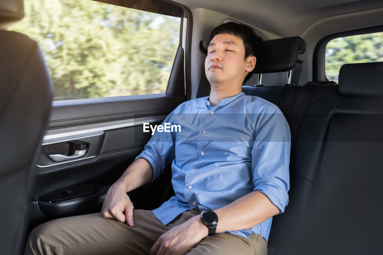 midsection of man using phone while sitting in car