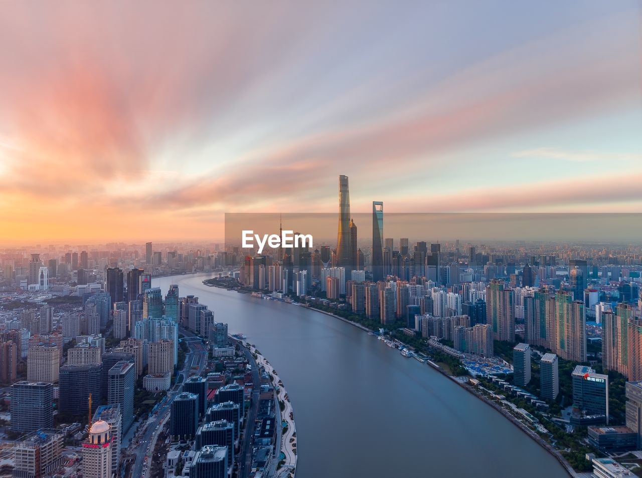 River amidst buildings in city against sky during sunset