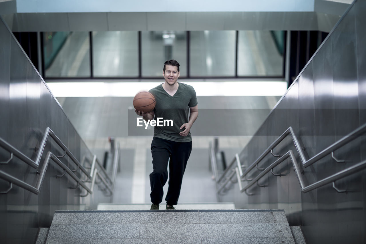 High angle portrait of young man with basketball moving up on steps