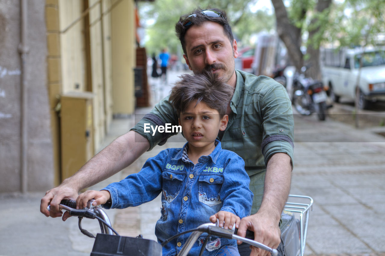 PORTRAIT OF FATHER AND SON RIDING