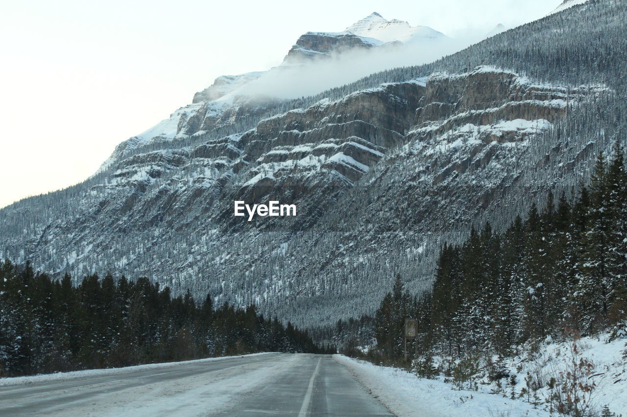 ROAD BY SNOWCAPPED MOUNTAINS AGAINST SKY