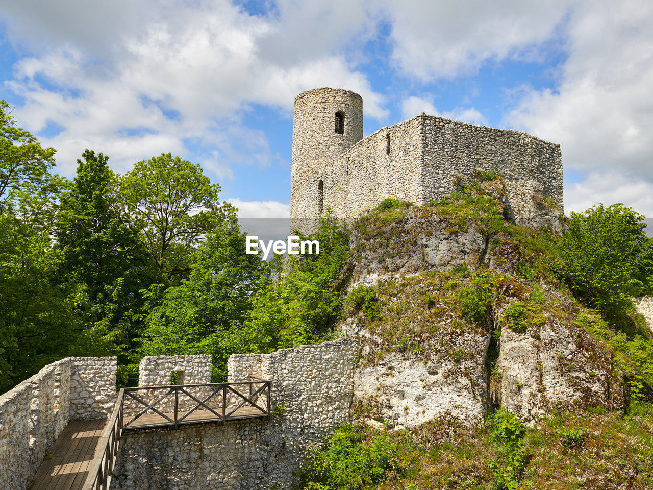 architecture, history, the past, built structure, castle, ruins, sky, building exterior, building, château, cloud, plant, tree, fort, fortification, nature, travel destinations, wall, ancient, old ruin, travel, medieval, old, fortified wall, no people, stone material, tourism, stone wall, outdoors, rock, low angle view, tower, moat, estate, ancient history, archaeological site, day, wall - building feature, surrounding wall, ruined, rural area, land, landscape, blue