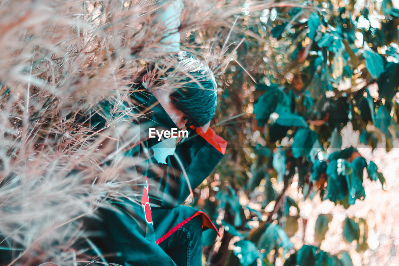 Portrait of young man sitting by plants