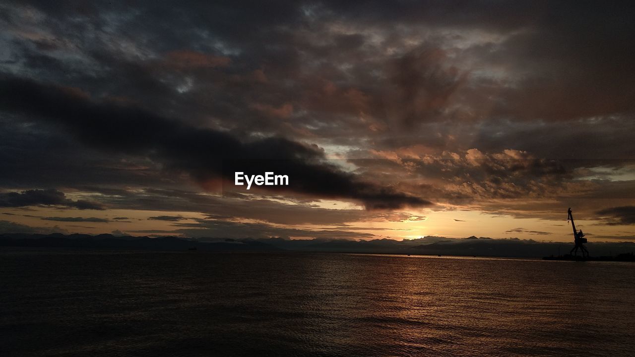 Scenic view of sea against dramatic sky during sunset