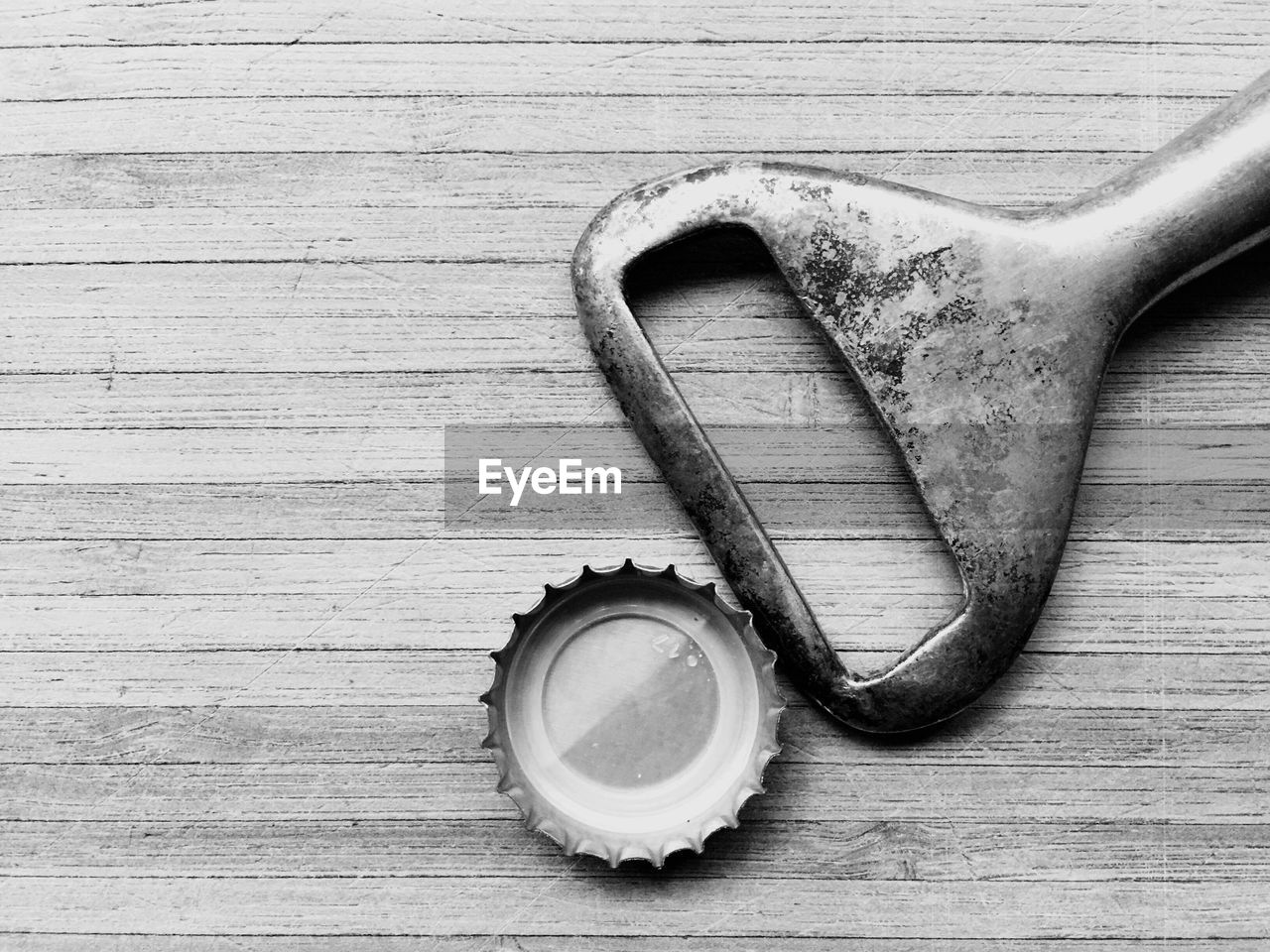 High angle view of cap with bottle opener on wooden table