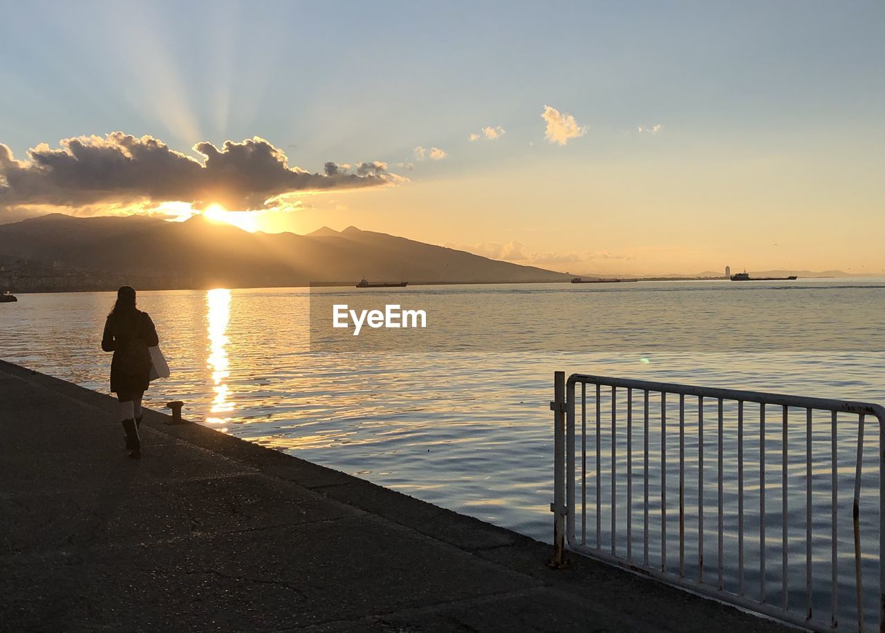 MAN ON SEA AGAINST SKY DURING SUNSET