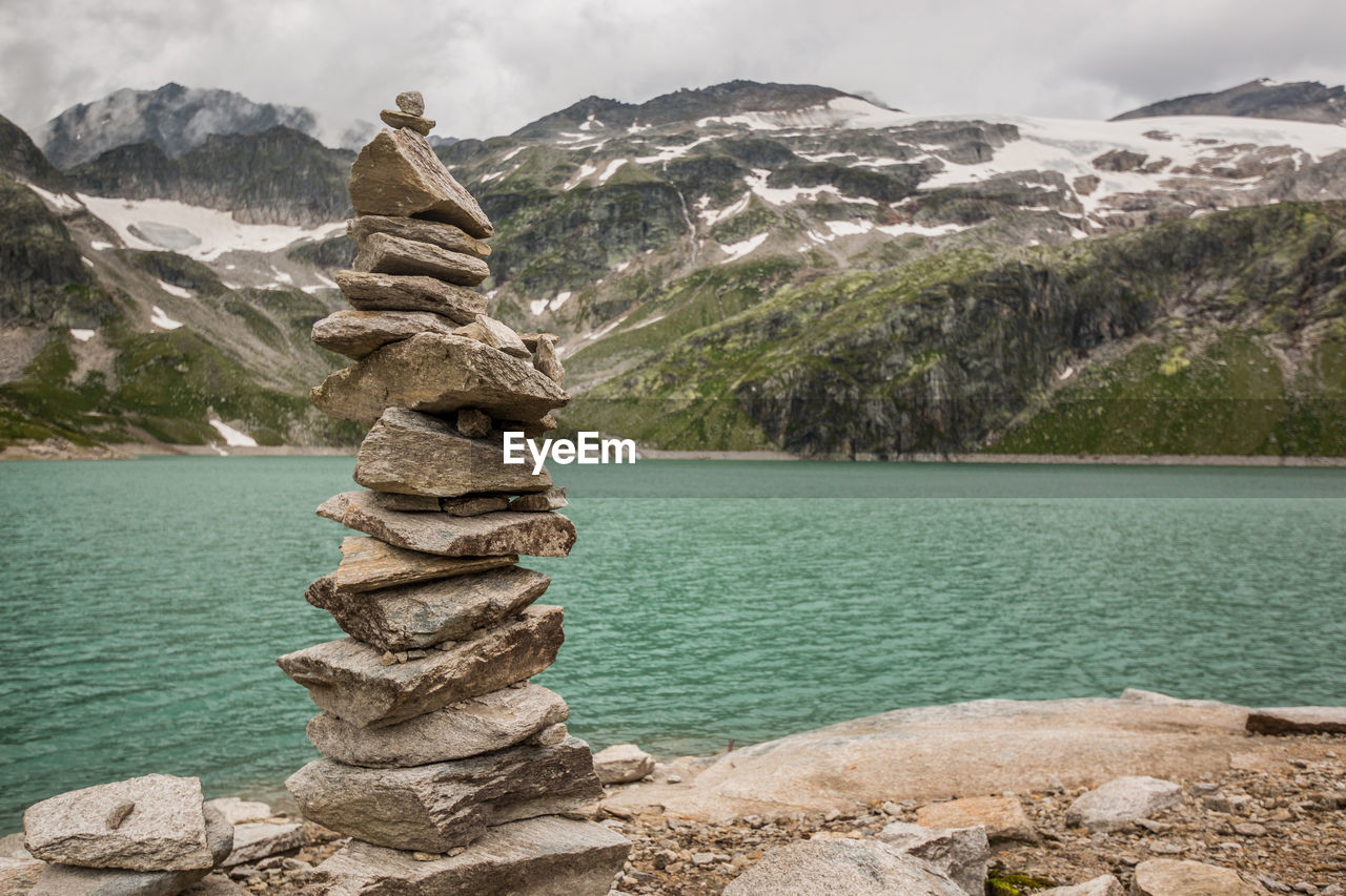 Stack of rocks against trees and mountain