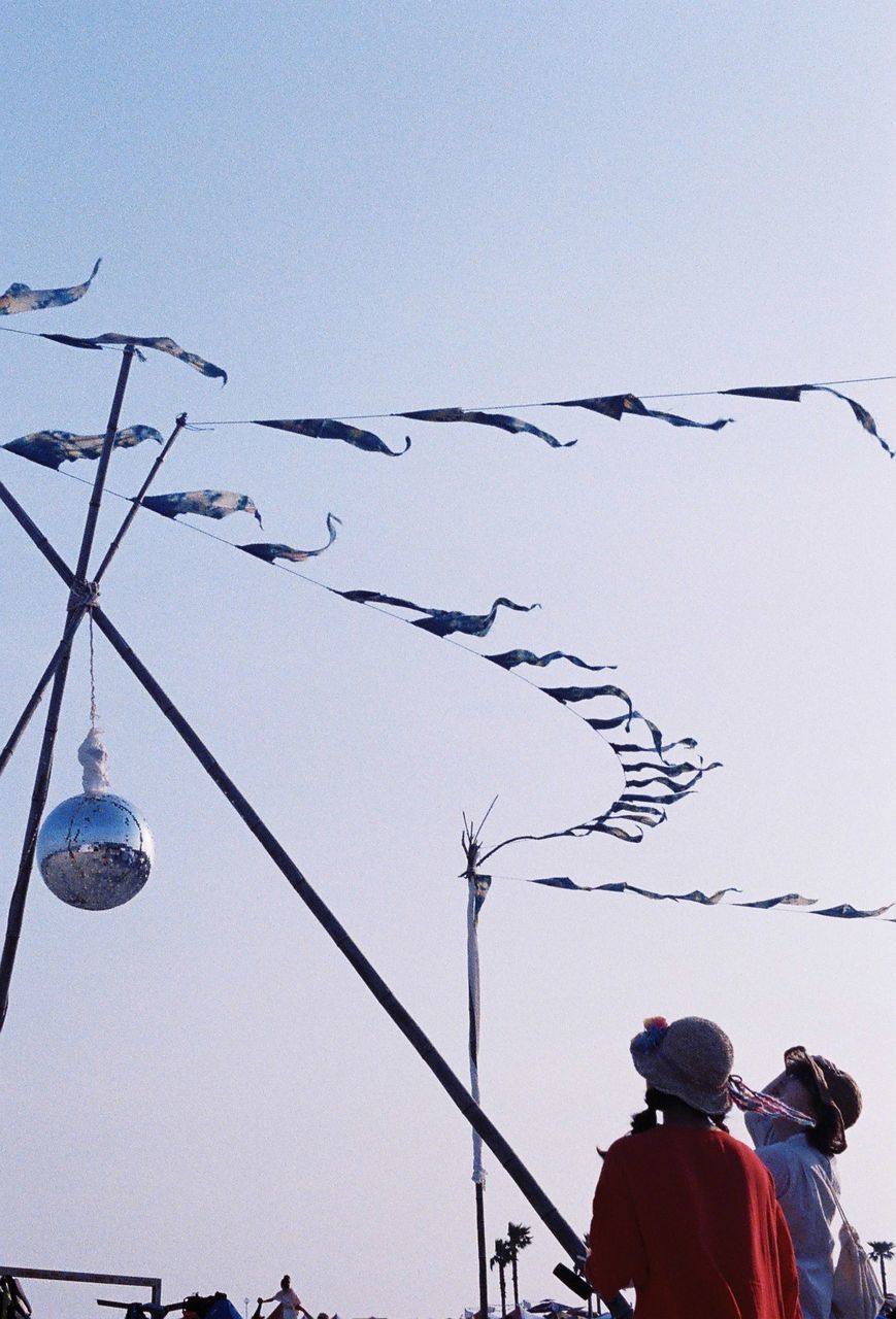 Low angle view of man flying against clear sky