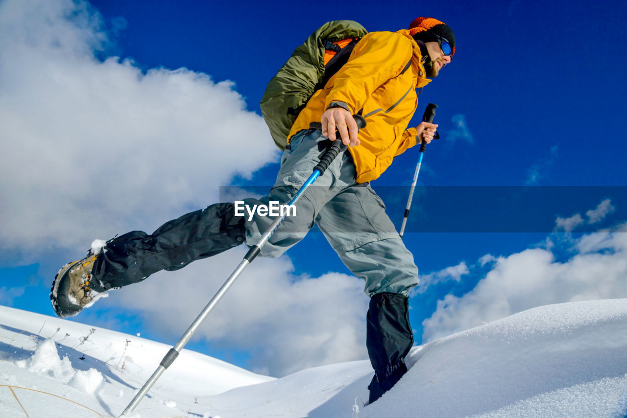 Low angle view of man hiking on snow against sky