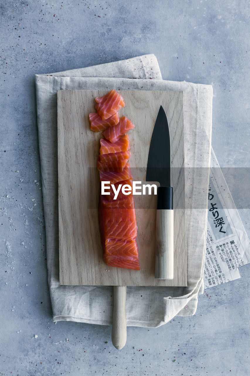 From above appetizing fresh sliced salmon on table with wooden board and knife