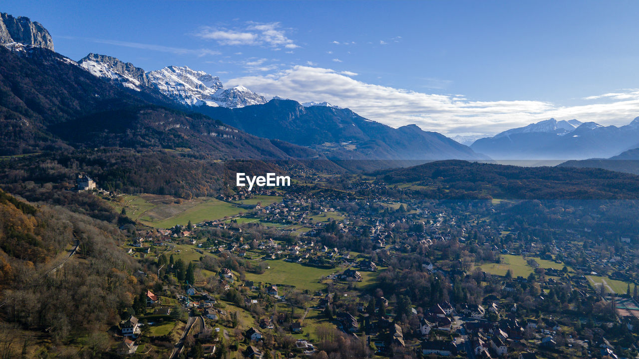 Scenic view of townscape by mountains against sky