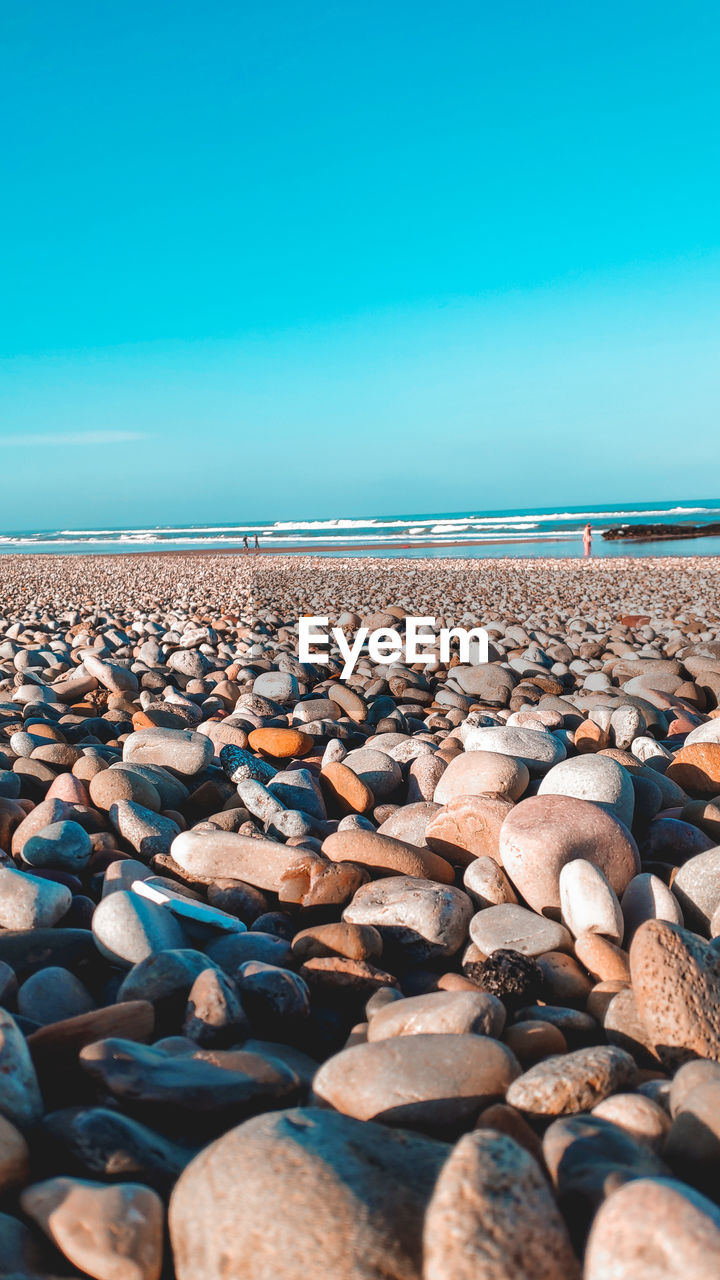 SURFACE LEVEL OF STONES ON SHORE AGAINST SKY