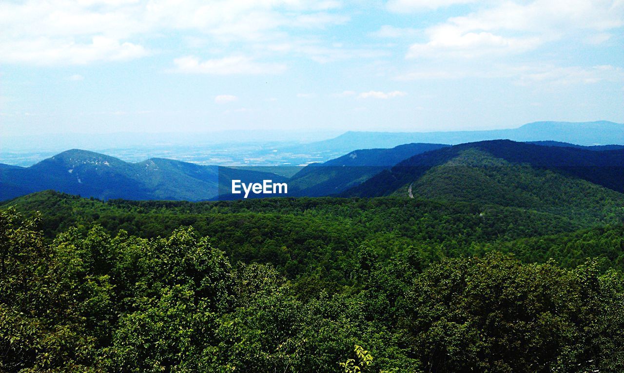 High angle view of green mountains against sky