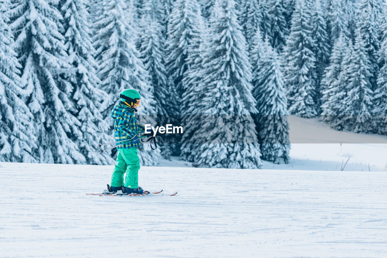 Full length of boy skiing against snow covered trees