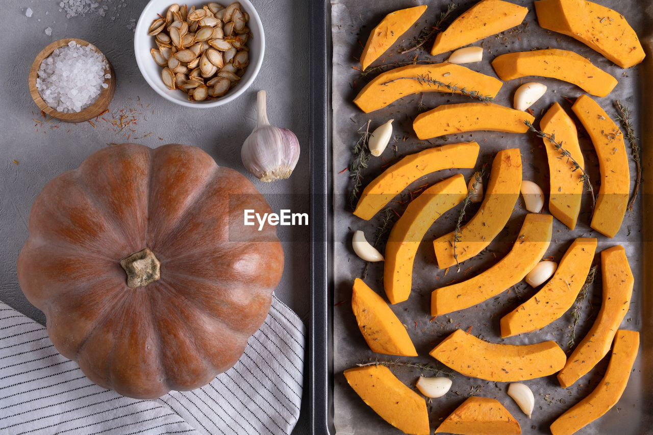 Ripe musk gourd and sliced gourd pieces on a baking sheet with olive oil, garlic