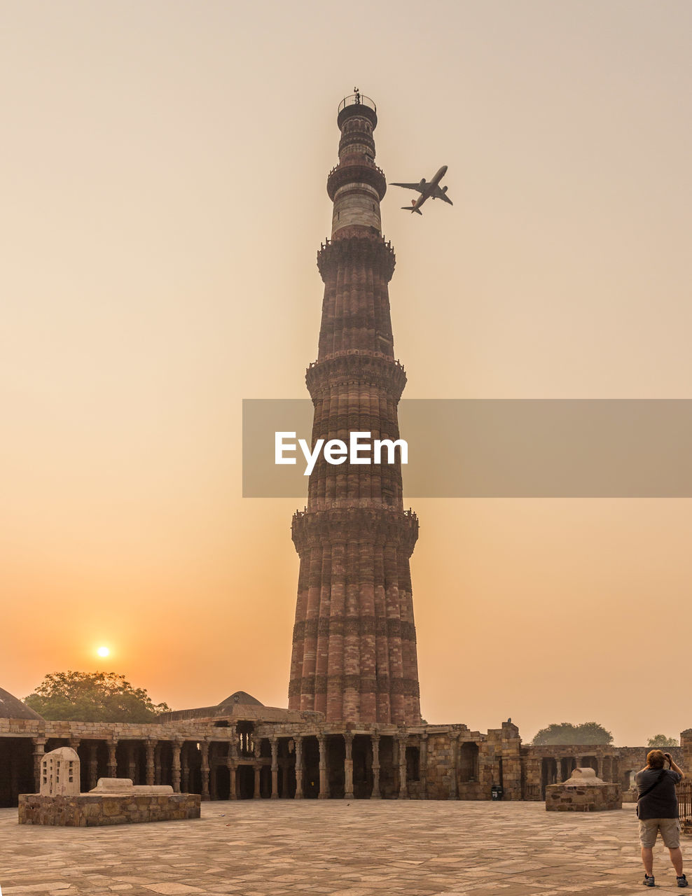 Low angle view of airplane in flight over tower