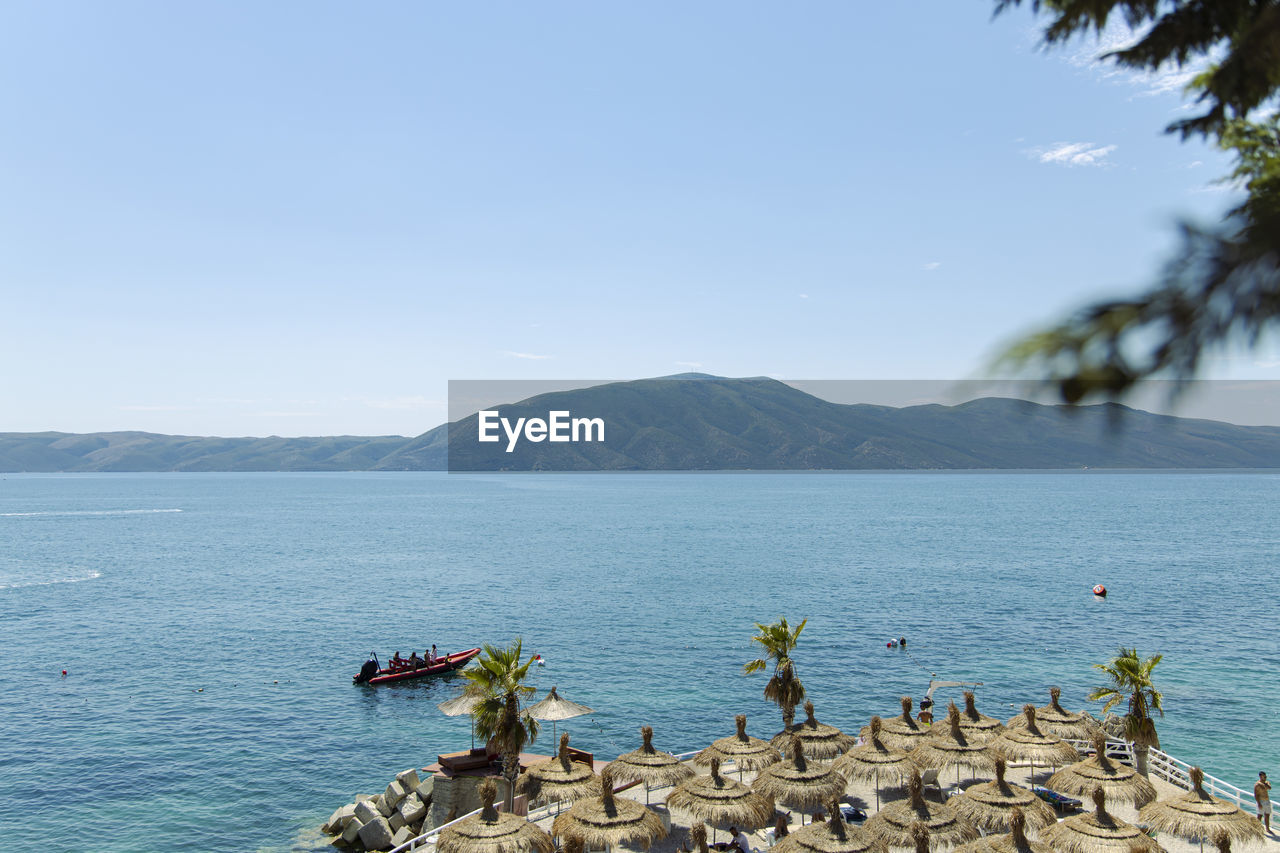 SCENIC VIEW OF SEA BY MOUNTAINS AGAINST CLEAR SKY