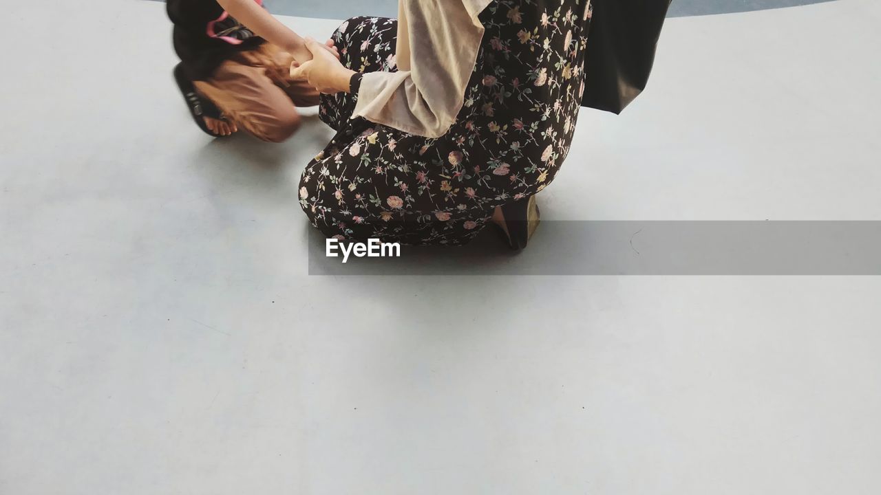 LOW SECTION OF WOMAN STANDING ON FLOOR IN BACKGROUND