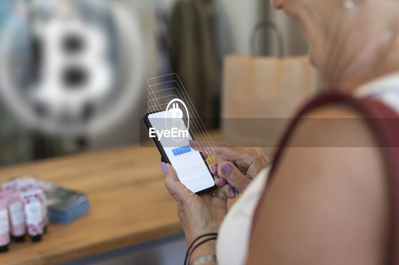 Woman paying with bitcoin crypto currency in store