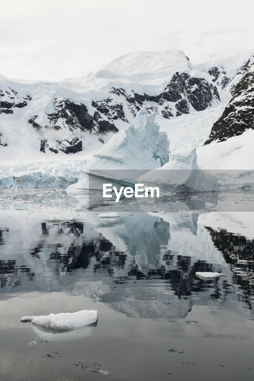 Iceberg and reflections on still seas in antarctica near paradise harbour