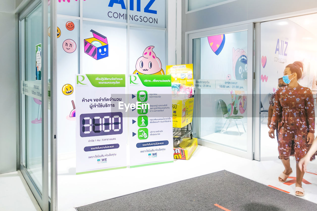 REAR VIEW OF WOMAN STANDING BY DOOR OF STORE