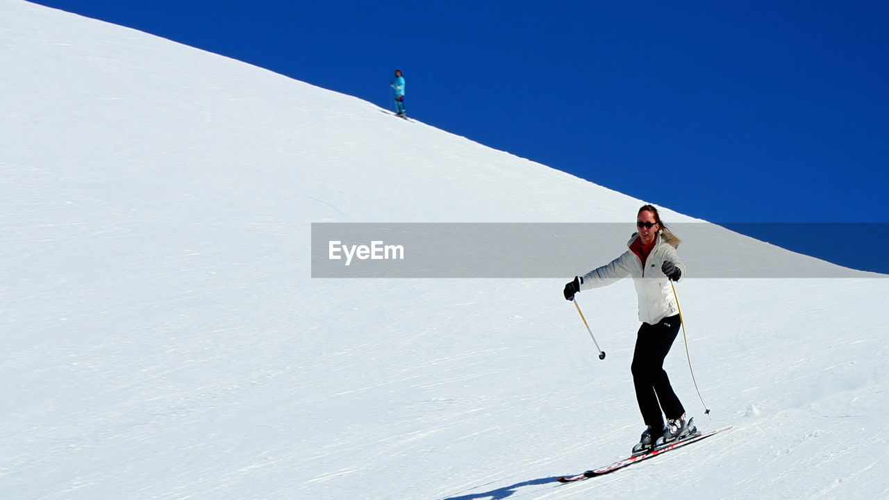 Low angle view of woman skiing on snow covered mountain