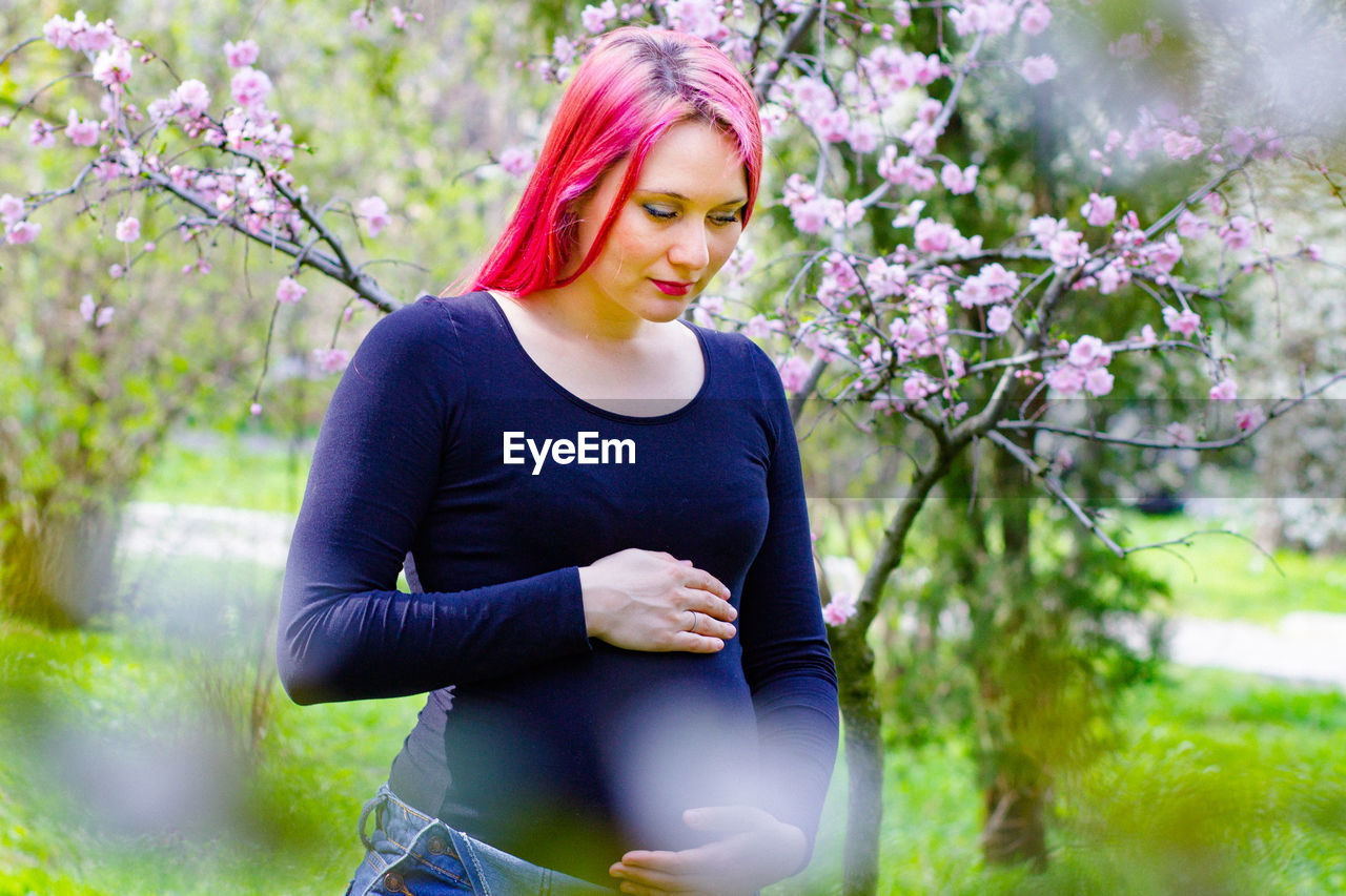Young beautiful pregnant girl with bright hair in spring park