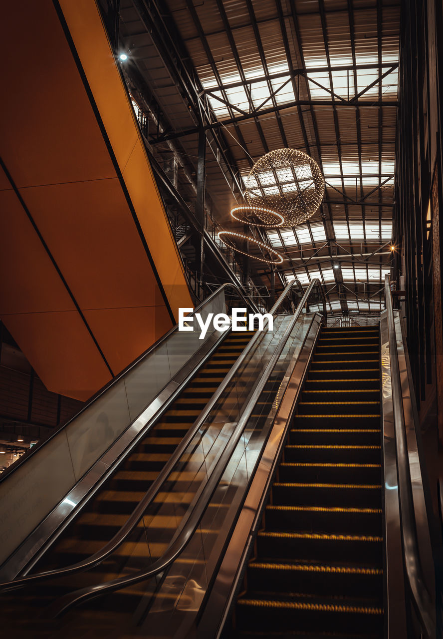 architecture, escalator, built structure, indoors, staircase, stairs, steps and staircases, railing, futuristic, transportation, no people, low angle view, metal, city, technology, convenience, light, illuminated, elevator, shopping mall, daylighting, railroad station, the way forward, interior design, building, public transportation