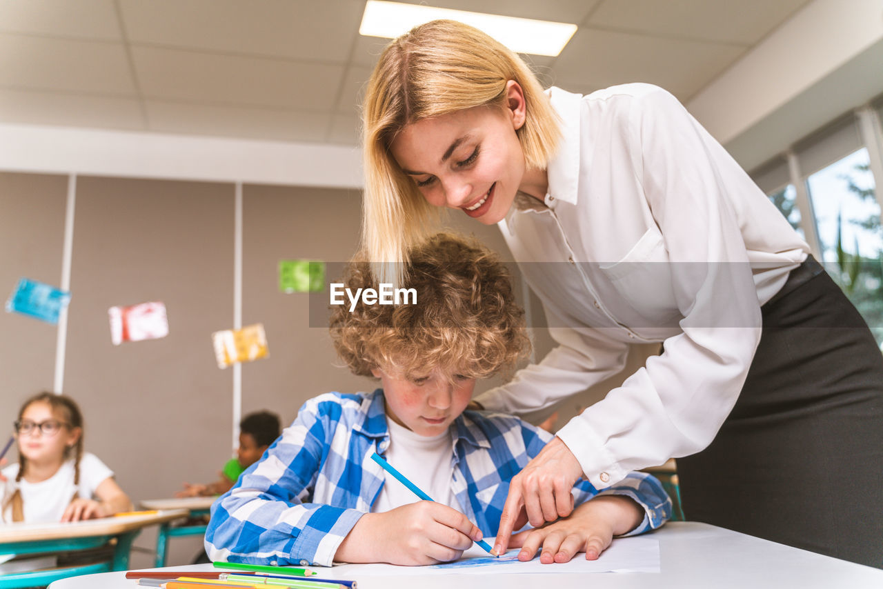 Teacher teaching student at classroom