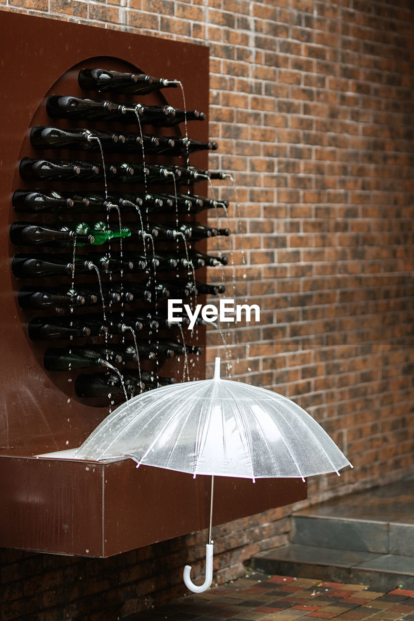 umbrella, protection, brick, brick wall, security, rain, wall, fashion accessory, wet, architecture, no people, wall - building feature, lighting, light, nature, outdoors