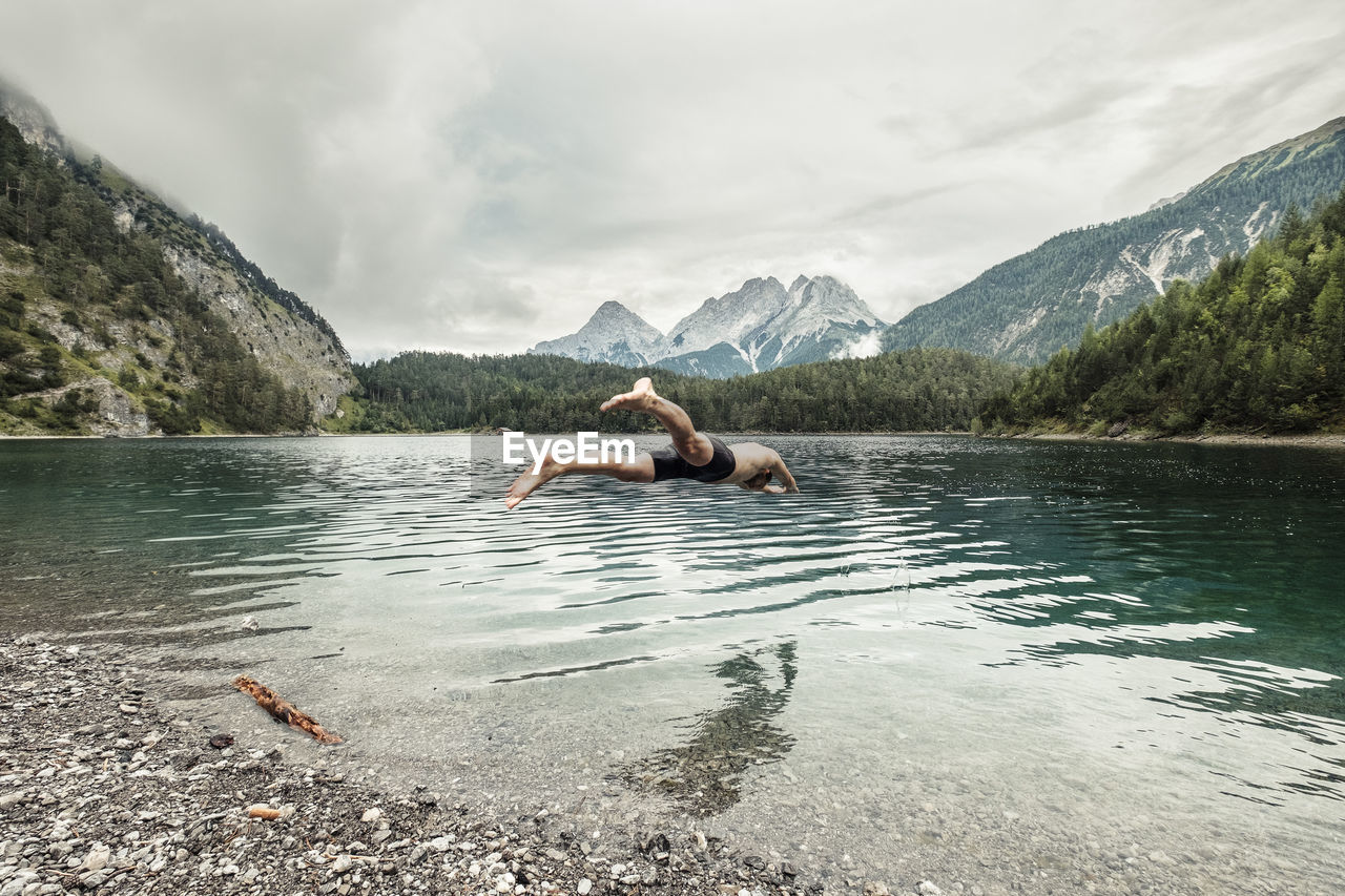 Man diving in blindsee lake by mieming range, tirol, austria