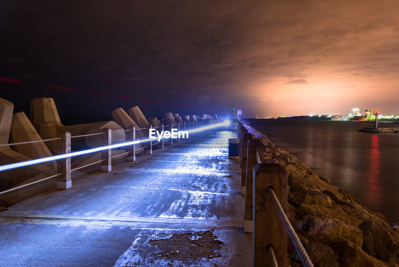 Light trail on footpath amidst sea at night