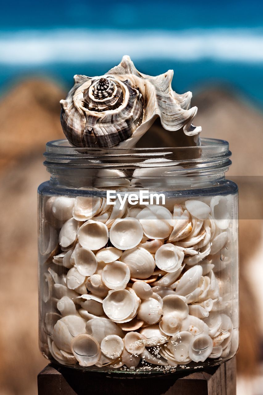 CLOSE-UP OF GLASS JAR ON TABLE AT SEA